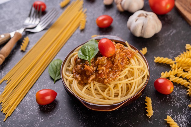 Spaghetti saute in a gray plate with tomatoes and basil Free Photo